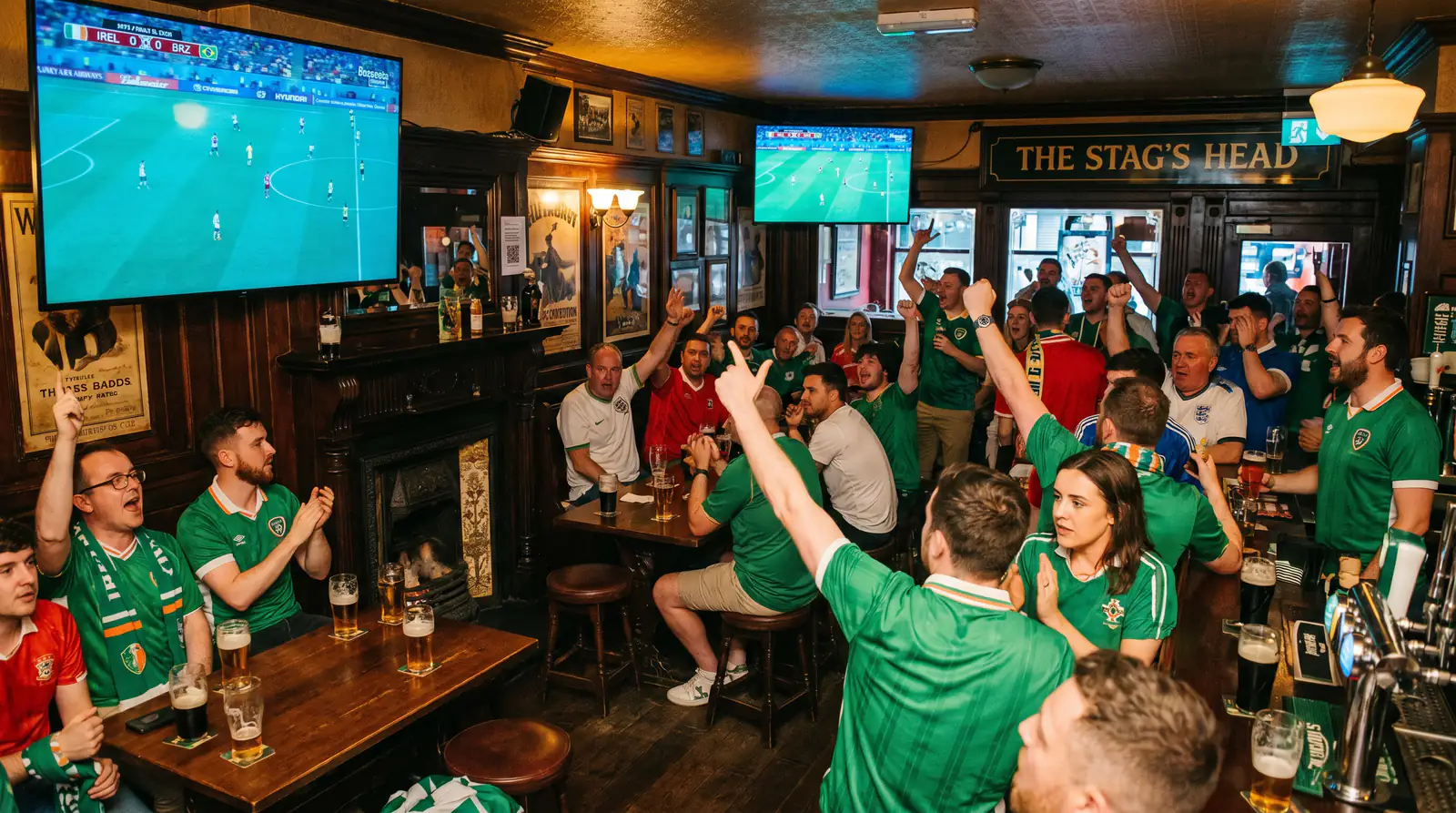 Crowded Irish pub with football fans watching a World Cup match on large screens with scarves and jerseys on display